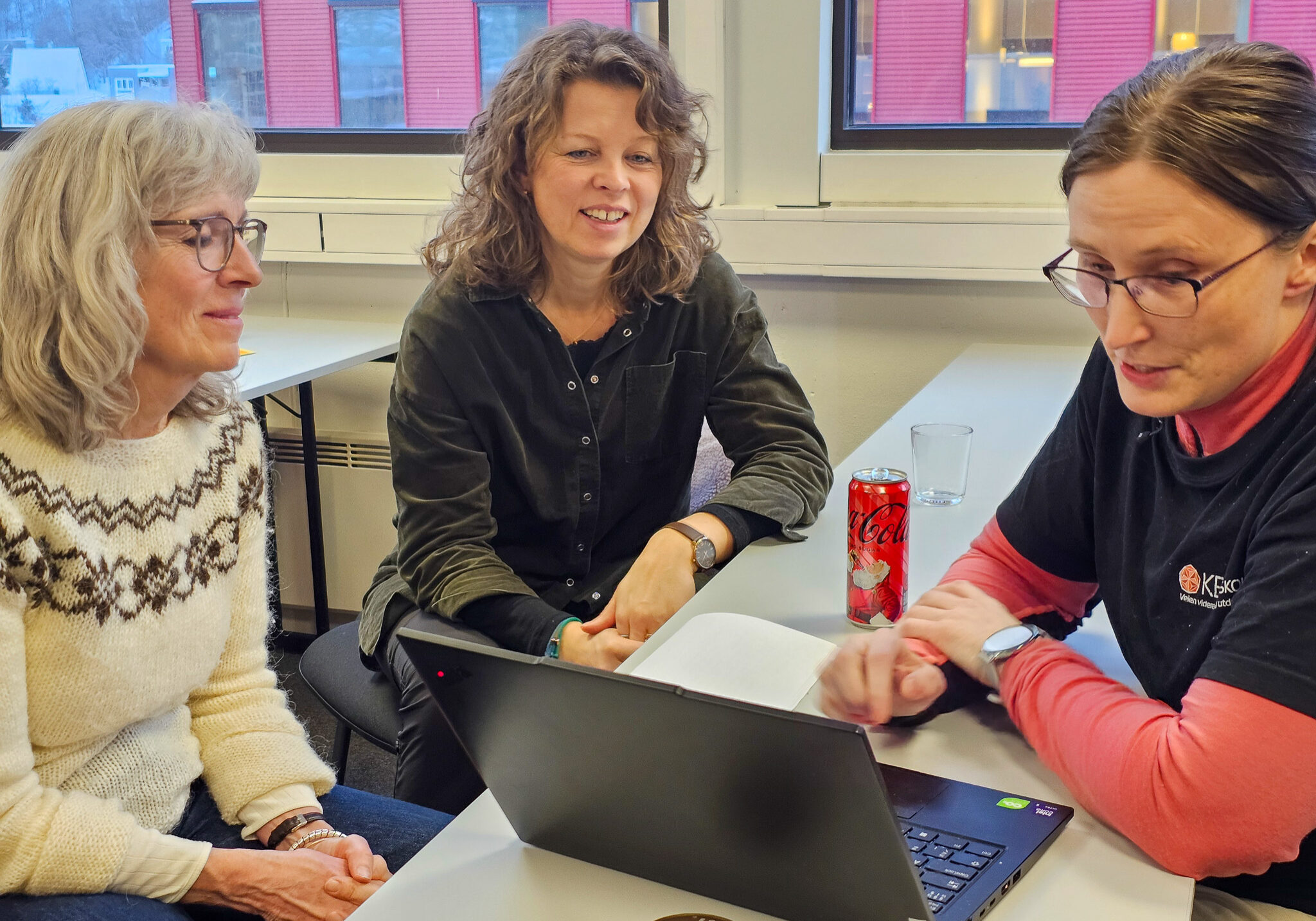 Bilde av tre damer som sitter rundt et bord og ser på en datamaskin